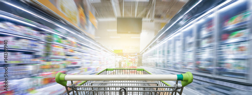 Supermarket aisle with empty green shopping cart