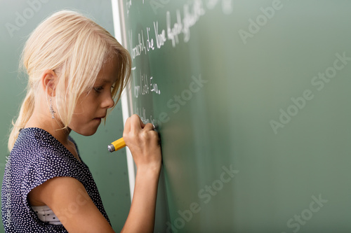 Mädchen schreibt mit Kreide an die Tafel