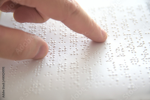 Hand of a blind person reading some braille text touching the relief. Empty copy space for Editor's content.