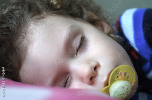 Krankes Kind schläft mit Nuckel im Mund
