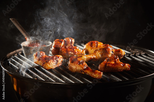 Spicy chicken legs grilling on a smoking fire