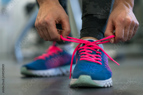 Running shoes - woman tying shoe laces. Woman getting ready for engage in the gym