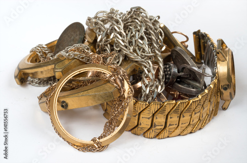 Scrap of precious metals. Old and broken jewelry, watches of gold and silver on a white background. Selective focus.