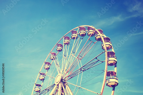 Vintage stylized picture of a Ferris wheel against the blue sky.