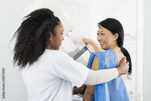 Happy Woman Looking At Doctor While Undergoing Mammogram X-ray T