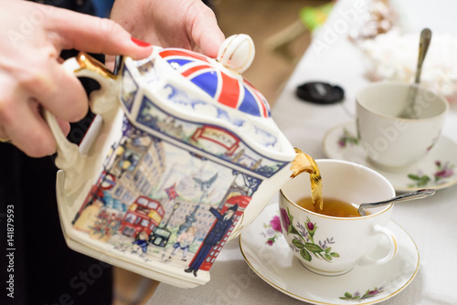 Tea poured into tea cup with British symbols