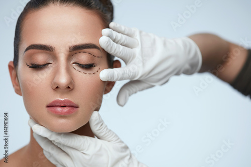 Closeup Of Beautician Hands Touching Young Female Patient Face