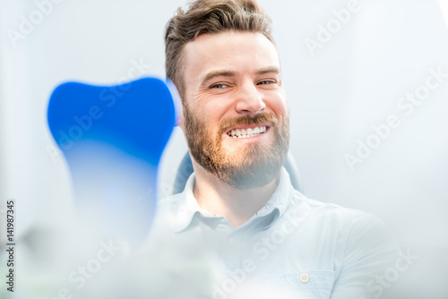 Handsome male patient looking at his beautiful smile sitting at the dental office