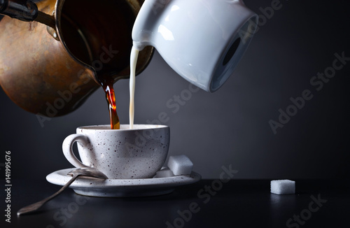 Cup of coffee with milk and sugar on dark background