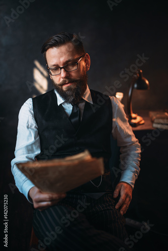 Bearded man in glasses reads handwritten text