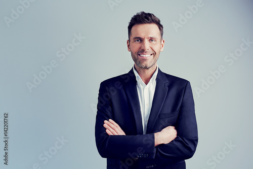 Happy businessman isolated - handsome man standing with crossed arms