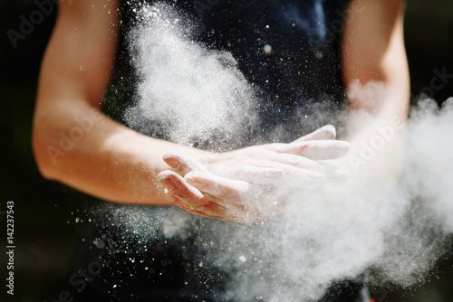 Climber woman coating her hands in powder chalk magnesium. Ready for climbing