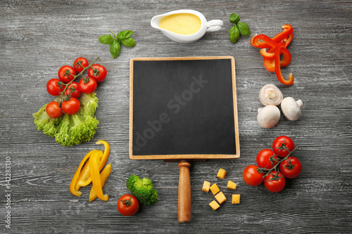 Still life with food ingredients and blank blackboard on table
