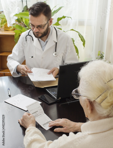 Lekarz podaje zastrzyk w brzuch starej kobiecie. Lekarz geriatra przyjmuje pacjenta w gabinecie. Stara kobieta u lekarza geriatry.Lekarz geriatra przyjmuje pacjenta. Odbiera dokumenty od pacjentki.