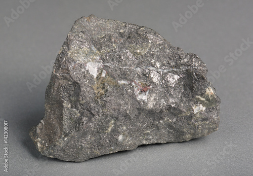 Mineral stone magnetite (lodestone)on gray background. Magnetite is the most magnetic of all minerals on Earth. 