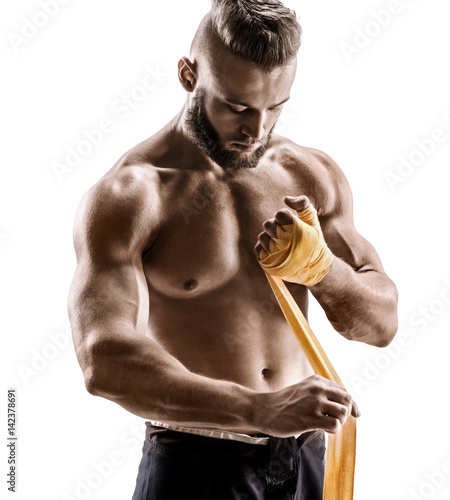 Kick-boxer preparing his fists for a fight. Photo of athletic man applying yellow boxing bandages isolated on white background. Strength and motivation.