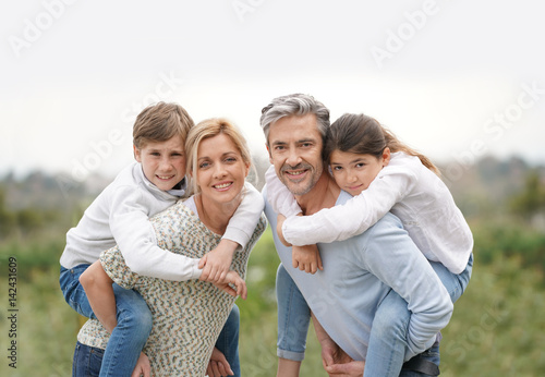 Parents giving piggyback ride to kids outside