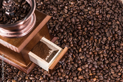 Elevated view of coffee mill with ground coffee on coffee beans