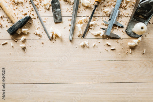 High angle view of shabby woodworking tools lying on wooden table, shavings scattered everywhere