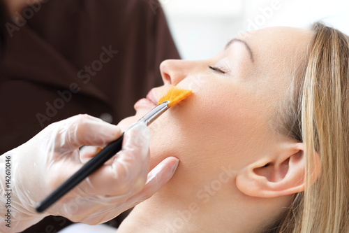 Pielęgnacja skóry, kosmetyczka nakłada pędzelkiem maseczkę na twarz kobiety