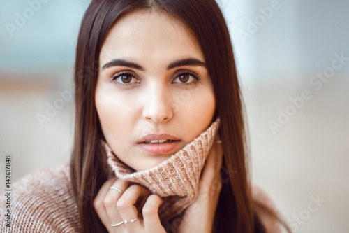 Closeup portrait of pensive white Caucasian European brunette young beautiful woman model with long dark red hair and brown eyes in turtleneck sweater, looking in camera