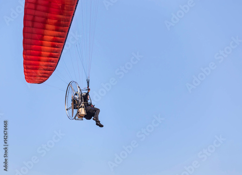 rear view paraglider flying with paramotor on blue sky background