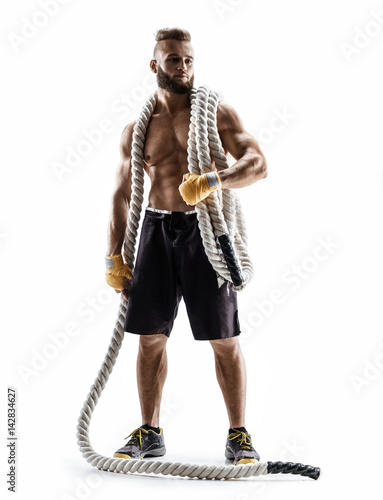 Athletic man with heavy ropes on his shoulders. Photo of young man in sportswear isolated on white background. Strength and motivation.