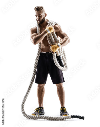 Handsome young man with heavy ropes on his shoulders. Photo of muscular man in sportswear isolated on white background. Strength and motivation.