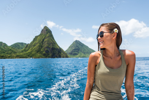 Happy woman cruising towards the deux gros pitons, popular tourist attraction in St Lucia. World Heritage site. Young traveler relaxing on shore excursion boat tour from cruise ship vacation travel.