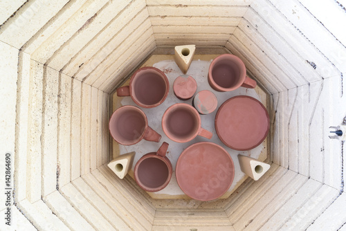 Overhead view of the bottom shelf of a kiln being loaded with pottery for a glaze firing