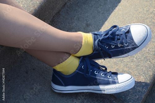 Beautiful legs in blue sneakers and yellow socks