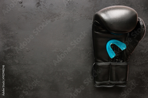 One boxing glove and a mouth guard on a black background with space for text