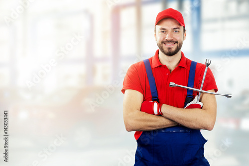 car repair service - smiling auto mechanic with wrench in hand
