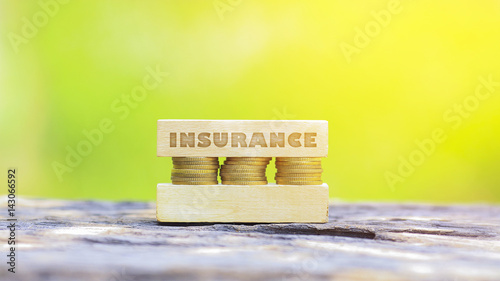 Business Concept - INSURANCE WORD, Golden coin stacked with wooden bar on shallow DOF green background