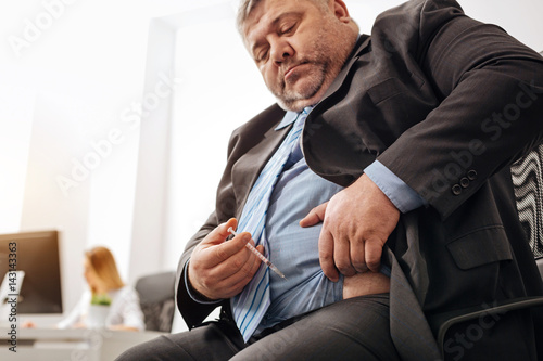Corpulent office worker giving himself daily injection