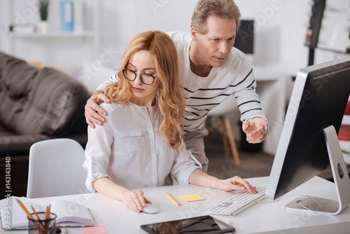 Flirting boss hugging young secretary in the office