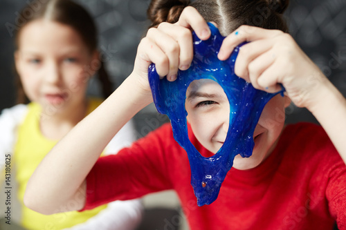 Happy kid looking through hole in blue slime