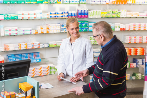 Junge Apothekerin bedient einen älteren Kunden