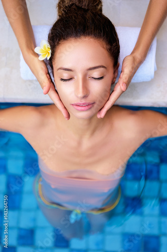 Beauty and health. Beautiful young woman getting facial massage in spa pool.