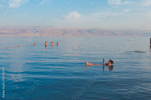 KALIA BEACH, ISRAEL - FEBRUARY 27, 2017: Young woman reads a book floating in the waters of the Dead Sea in Israel