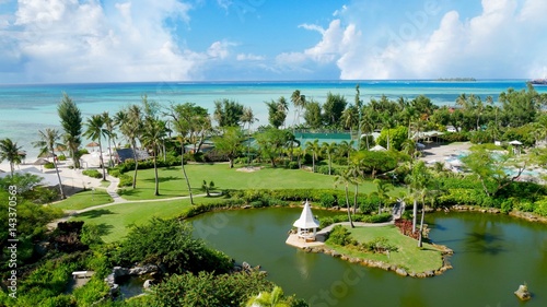 Landscaped gardens Pristine blue waters of the Micro Beach and the far-off Managaha Island backdrops a perfectly manicured garden with pond in Saipan, Northern Mariana Islands.