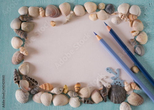 Summer frame with seashells and pen on a turquoise painted wooden background