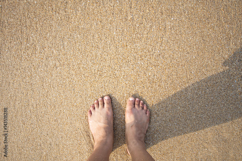 foot of human on sand and soft wave on the sea.