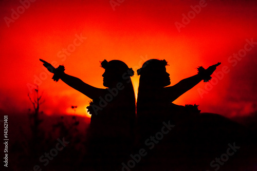 Profile of Hawaiian women hula dancing in front of volcano