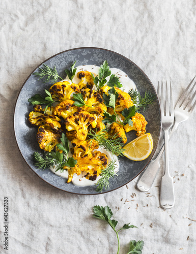 Roasted turmeric cauliflower with greek yogurt dressing. Delicious healthy food on a grey background, top view