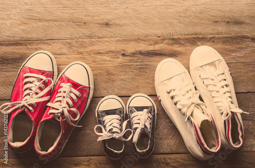 Three pairs of shoes lay on the wooden floor of the family, parents and children to do together.
