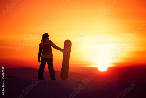Woman snowboarder silhouette on sunset backdrop