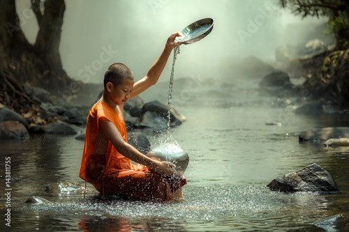 Thailand monk or novice monk sitting in the creek are wash container or bowl to clean