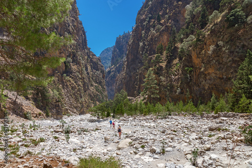 The famous Samaria Gorge in the white mountains on the island of Crete in Greece. Tourists walking along the hiking trail ahead. Dry riverbed.