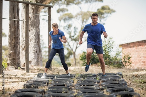 Man and woman running over the tire during obstacle course